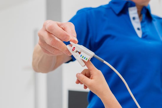 Eine Pflegefachperson misst die Sauerstoffsättigung am Finger eines Patienten.