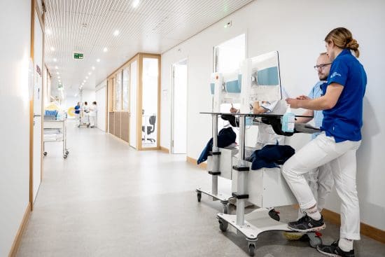 Pflegefachpersonen stehen auf einem Gang im Spital und schauen auf einen Bildschirm.